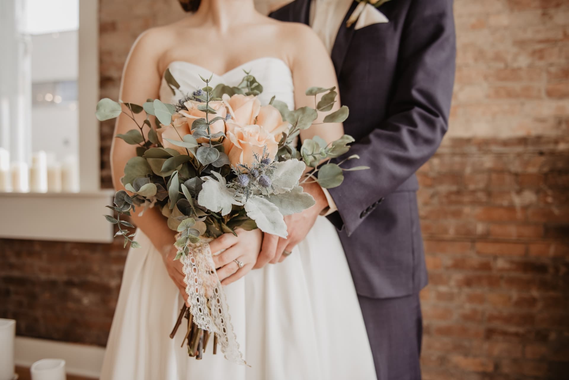 Bride holding a bouquet with her partner standing behind her indoors